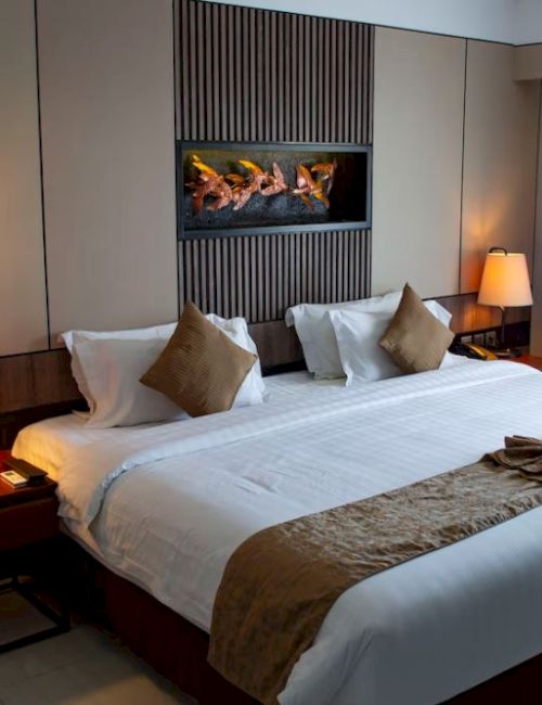 A neatly arranged hotel room features a large bed, bedside tables with lamps, and a wall-mounted decoration above the headboard.